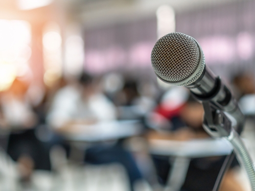 Stock image of microphone in front of an audience